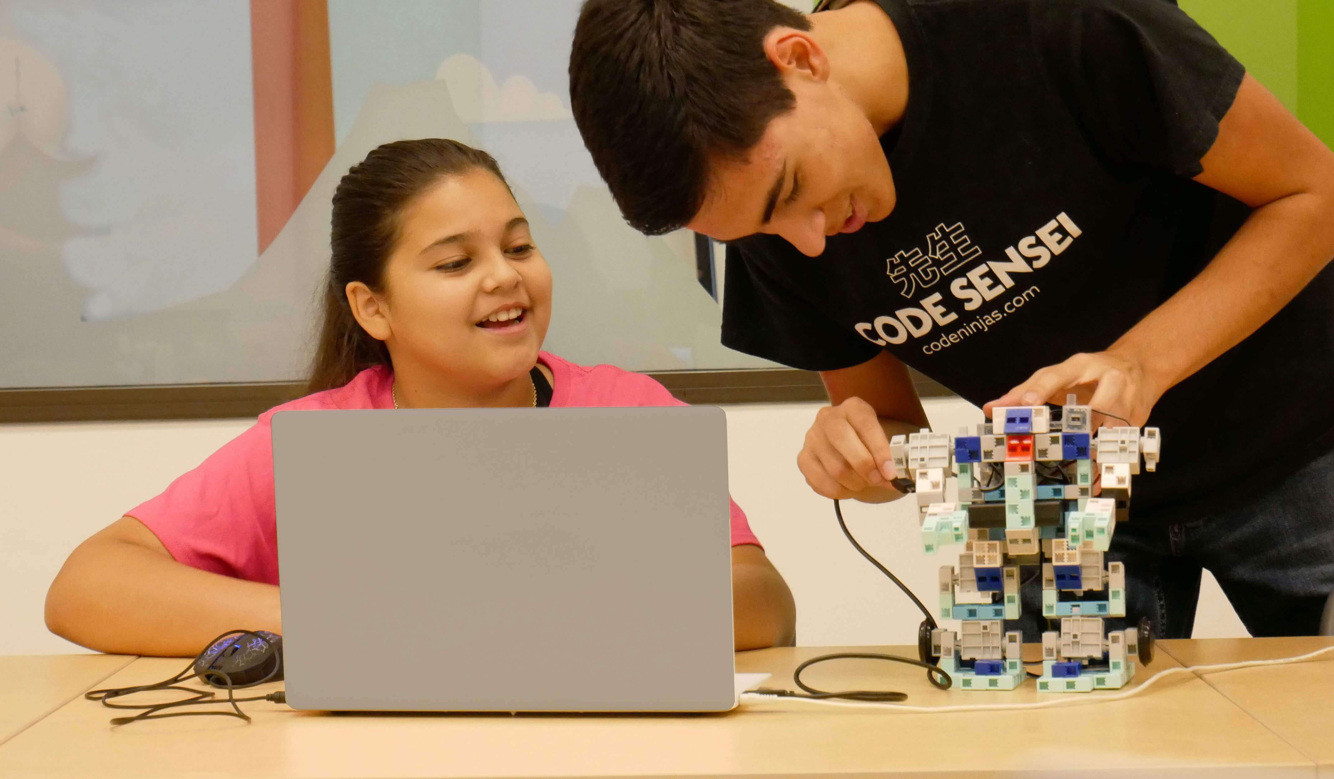 Code Ninjas Sensei helping child on laptop with a robot